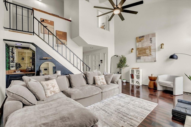 living room with a ceiling fan, wood finished floors, a high ceiling, and stairway