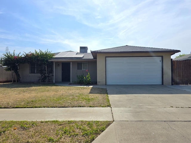 4571 N Kavanagh Ave, Fresno, CA 93705 - single story home with concrete driveway, a garage, solar panels, and stucco siding