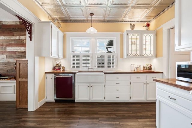 kitchen featuring white cabinets, wooden counters, stainless steel appliances, an ornate ceiling, and dark wood-type flooring