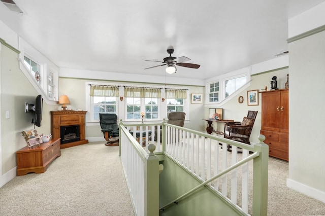 living area featuring baseboards, carpet flooring, ceiling fan, and visible vents