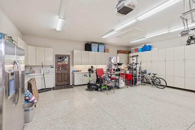 garage featuring stainless steel fridge, a sink, and a garage door opener