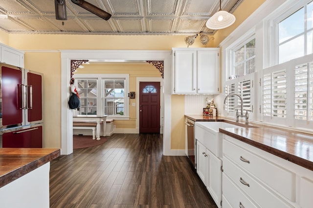kitchen with wood counters, an ornate ceiling, high quality fridge, white cabinetry, and a sink