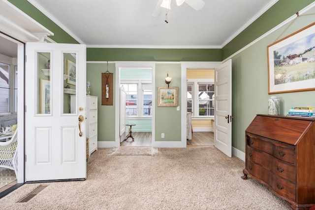 carpeted foyer featuring baseboards, a ceiling fan, and crown molding