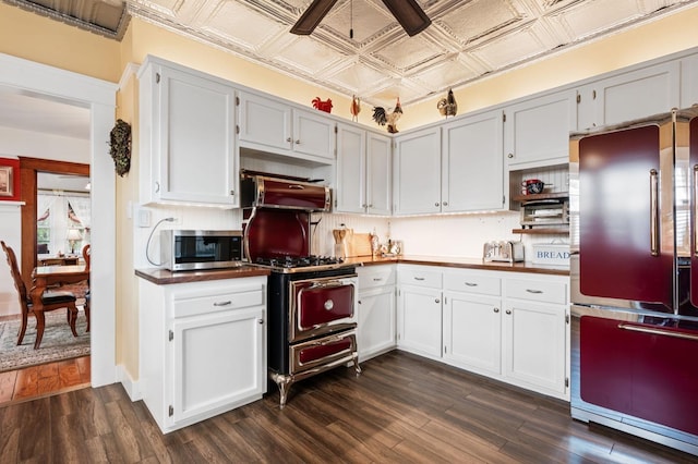 kitchen with dark wood-type flooring, dark countertops, an ornate ceiling, and appliances with stainless steel finishes