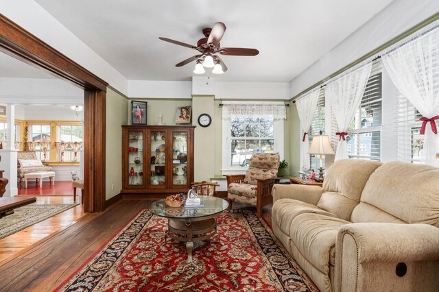living room with hardwood / wood-style flooring, baseboards, and ceiling fan