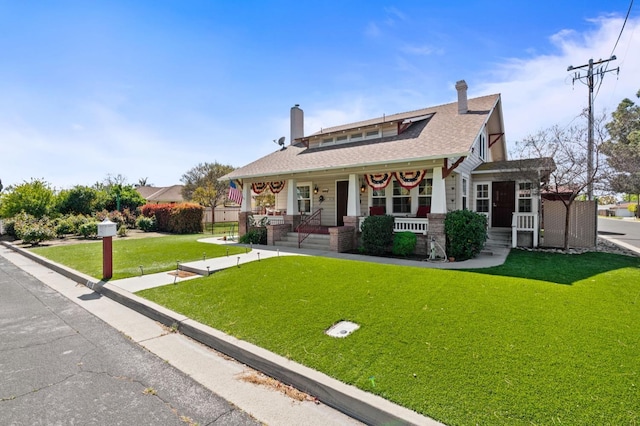 view of front of property with a chimney, a porch, roof with shingles, and a front lawn