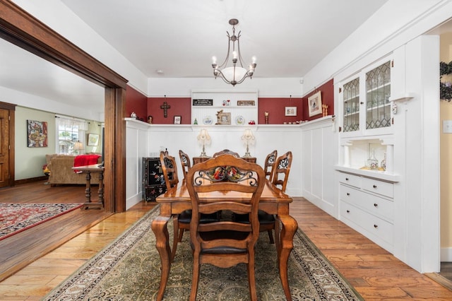 dining space featuring light wood-type flooring and an inviting chandelier