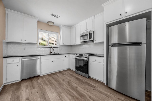 kitchen featuring a sink, dark countertops, appliances with stainless steel finishes, and visible vents