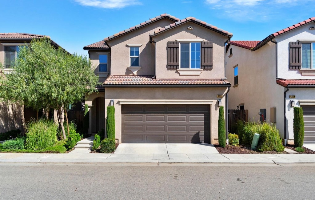 6220 E Sydney Dr, Fresno, CA 93727 - mediterranean / spanish house featuring stucco siding, an attached garage, and a tile roof