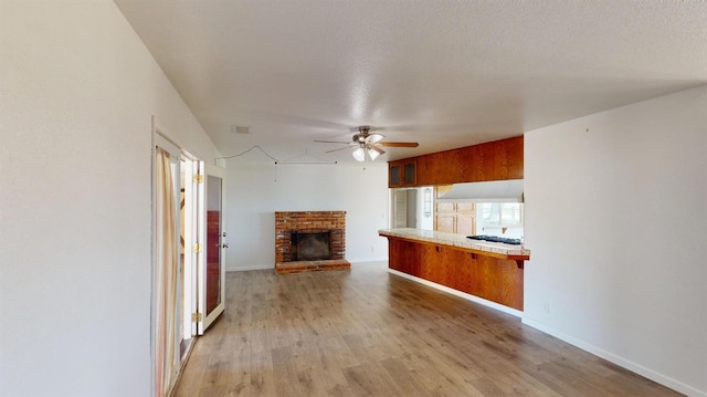 2299 N Garfield Ave, Fresno, CA 93723 - unfurnished living room featuring a ceiling fan, a brick fireplace, light wood-style floors, and baseboards
