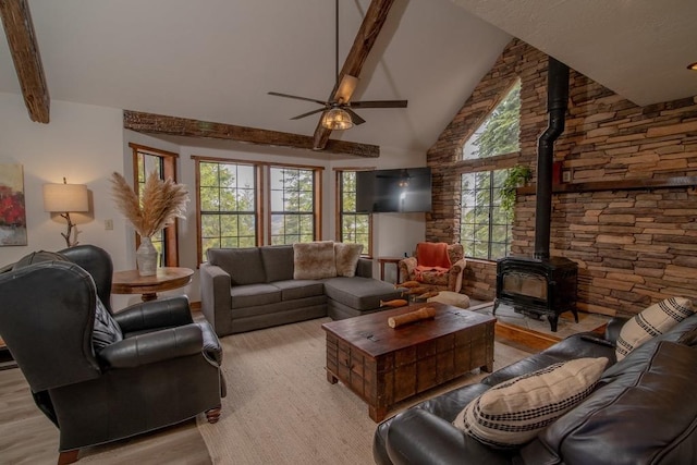 living area featuring light wood-style flooring, a wood stove, beamed ceiling, ceiling fan, and high vaulted ceiling