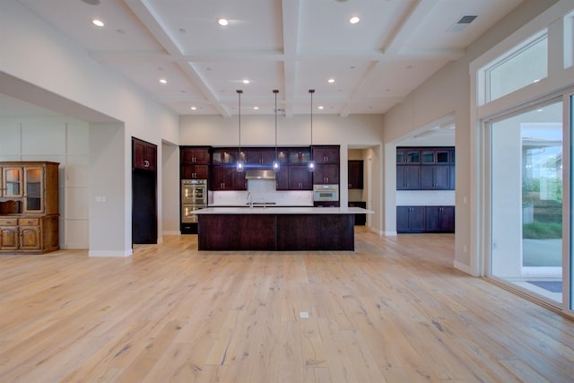2791 E Tuolumne Rd, Turlock, CA 95382 - kitchen with coffered ceiling, extractor fan, light wood-style floors, stainless steel double oven, and open floor plan