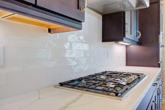 2791 E Tuolumne Rd, Turlock, CA 95382 - kitchen with stainless steel gas stovetop, extractor fan, tasteful backsplash, dark brown cabinets, and light stone counters
