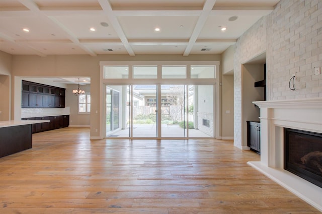 2791 E Tuolumne Rd, Turlock, CA 95382 - unfurnished living room featuring a glass covered fireplace, coffered ceiling, a chandelier, light wood finished floors, and recessed lighting