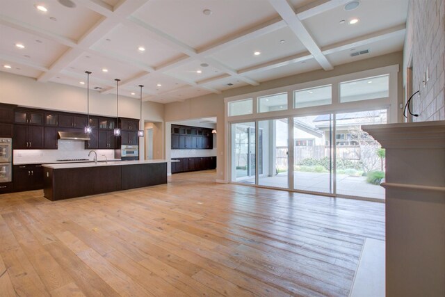 2791 E Tuolumne Rd, Turlock, CA 95382 - kitchen featuring coffered ceiling, under cabinet range hood, open floor plan, a high ceiling, and light wood-style flooring
