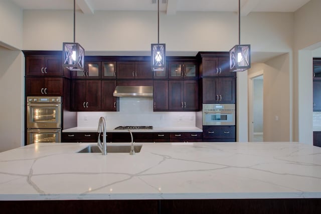 2791 E Tuolumne Rd, Turlock, CA 95382 - kitchen with double oven, a sink, under cabinet range hood, gas stovetop, and hanging light fixtures