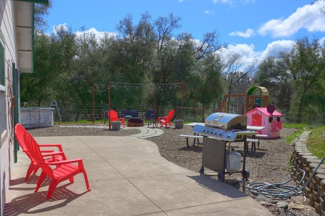 view of patio featuring area for grilling, playground community, and fence
