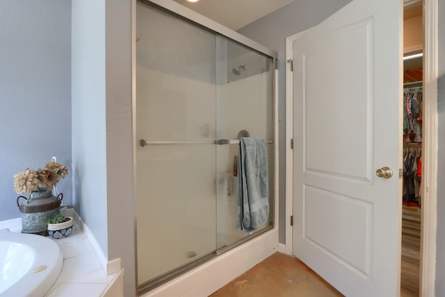 full bath featuring a shower stall and a spacious closet