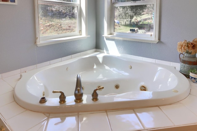 full bathroom featuring a tub with jets and a textured wall