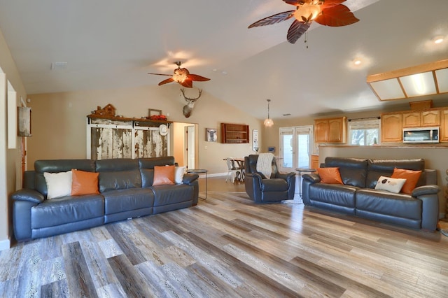 living room featuring baseboards, vaulted ceiling, light wood-style floors, and a ceiling fan