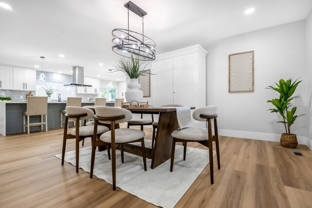 dining room with light wood finished floors, a notable chandelier, baseboards, and recessed lighting