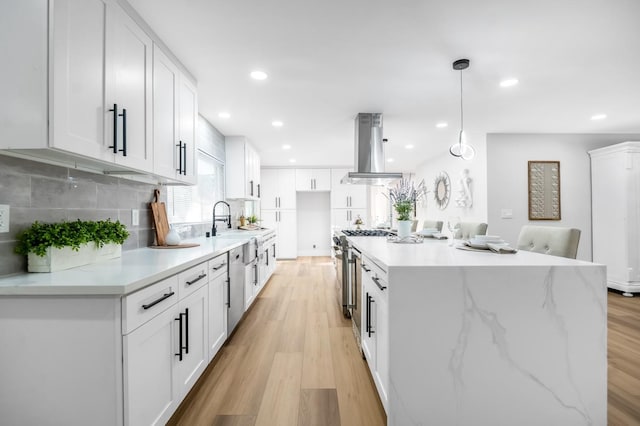 kitchen with light wood-style flooring, white cabinets, island range hood, and high end stove