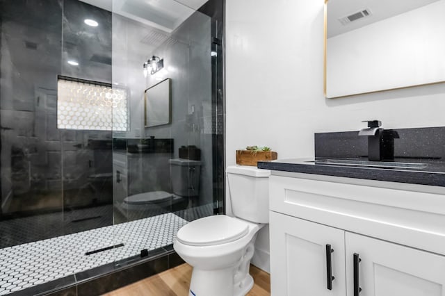 bathroom featuring a shower stall, vanity, visible vents, toilet, and wood finished floors
