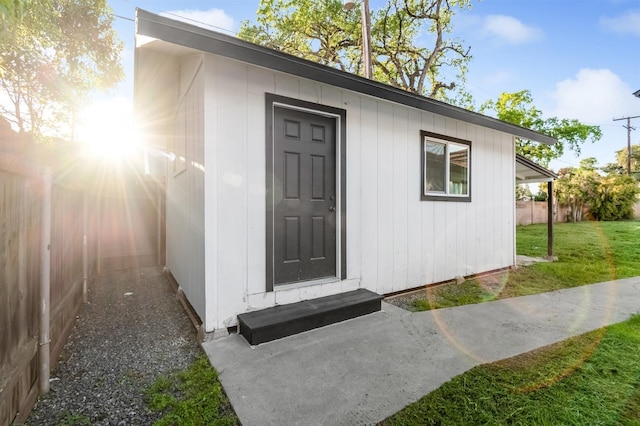 view of exterior entry with a yard and fence