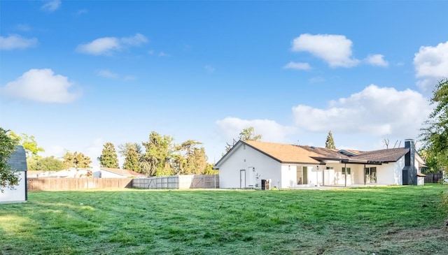 rear view of property featuring stucco siding, fence, and a lawn
