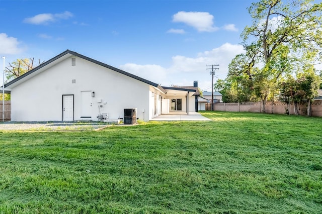 back of property featuring fence, cooling unit, a lawn, and stucco siding
