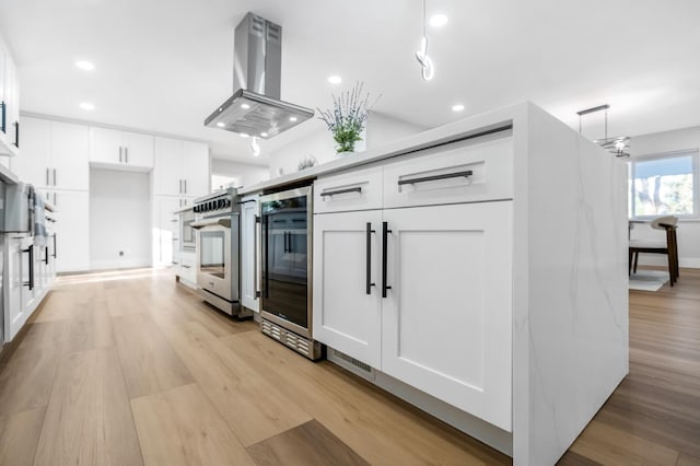 kitchen with light wood-type flooring, white cabinetry, ventilation hood, recessed lighting, and oven
