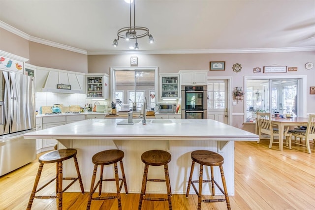 49521 Stillmeadow Dr, Oakhurst, CA 93644 - kitchen with light wood-style flooring, a breakfast bar, appliances with stainless steel finishes, light countertops, and extractor fan