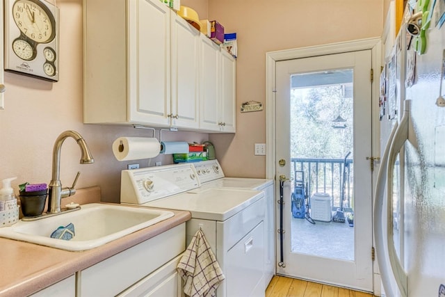 49521 Stillmeadow Dr, Oakhurst, CA 93644 - clothes washing area with a sink, washing machine and clothes dryer, cabinet space, and light wood finished floors