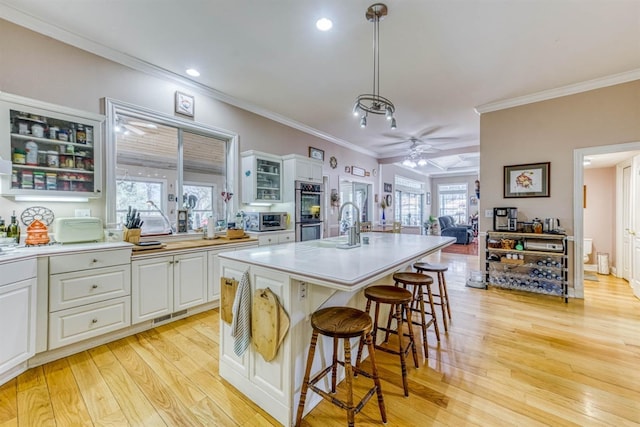 49521 Stillmeadow Dr, Oakhurst, CA 93644 - kitchen with a breakfast bar, light wood-style flooring, glass insert cabinets, stainless steel double oven, and ceiling fan