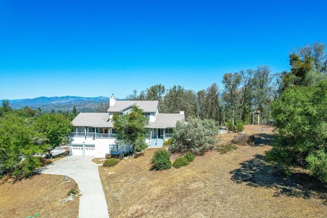 49521 Stillmeadow Dr, Oakhurst, CA 93644 - exterior space featuring concrete driveway, a mountain view, a chimney, a porch, and a garage