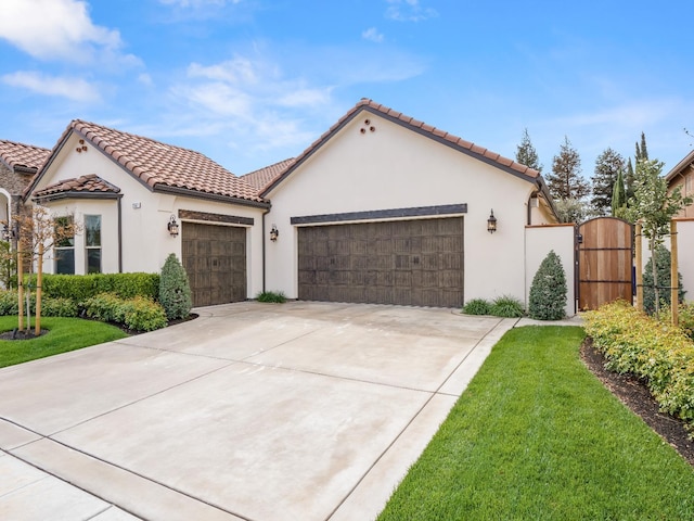 2567 E Sarazen, Fresno, CA 93730 - mediterranean / spanish home featuring an attached garage, concrete driveway, a gate, stucco siding, and a tiled roof