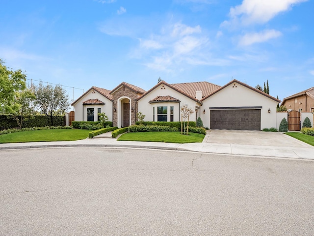 2567 E Sarazen, Fresno, CA 93730 - mediterranean / spanish-style house with stucco siding, an attached garage, concrete driveway, a tiled roof, and stone siding