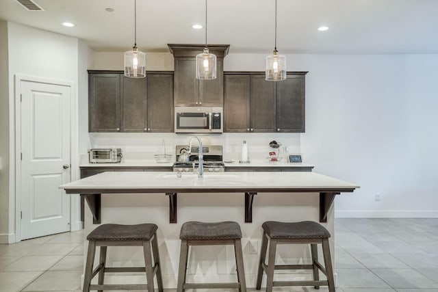 kitchen with appliances with stainless steel finishes, a breakfast bar, a center island with sink, light tile patterned floors, and recessed lighting