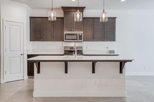 377 Wishon Way W, Madera, CA 93636 - kitchen with appliances with stainless steel finishes, dark brown cabinetry, an island with sink, a breakfast bar, and light countertops