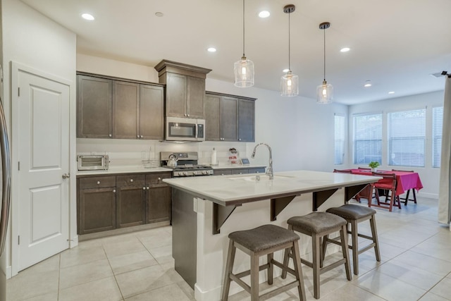 377 Wishon Way W, Madera, CA 93636 - kitchen with stainless steel microwave, stove, a breakfast bar area, dark brown cabinets, and a kitchen island with sink