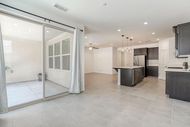 377 Wishon Way W, Madera, CA 93636 - kitchen featuring open floor plan, a center island with sink, light countertops, dark brown cabinetry, and light tile patterned flooring