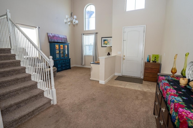 foyer entrance with a high ceiling, an inviting chandelier, stairs, light carpet, and baseboards