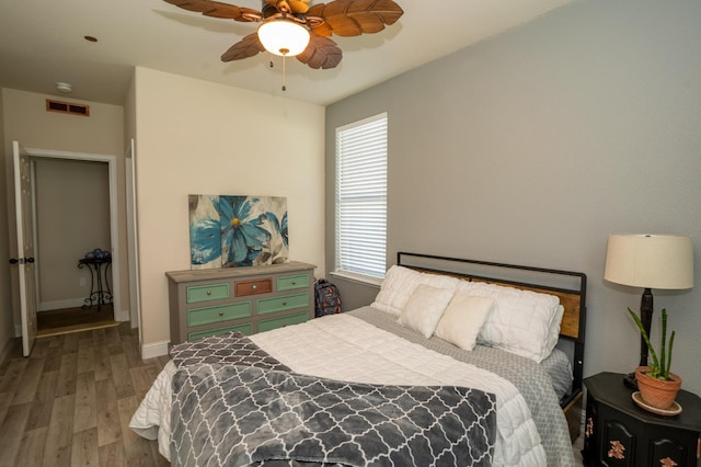 bedroom with baseboards, visible vents, wood finished floors, and a ceiling fan