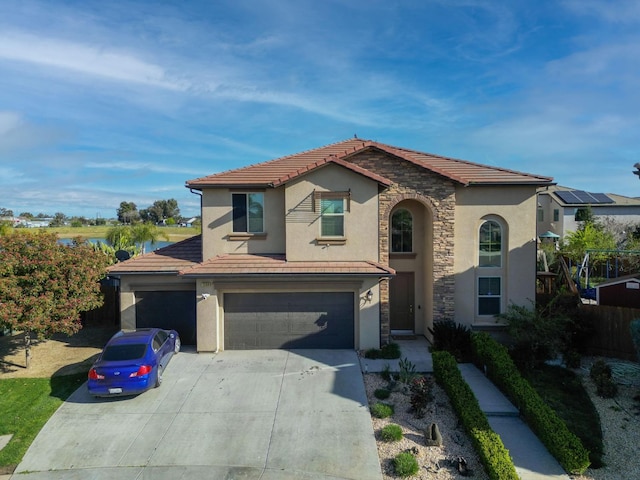 mediterranean / spanish-style house with stucco siding, a tiled roof, driveway, stone siding, and an attached garage