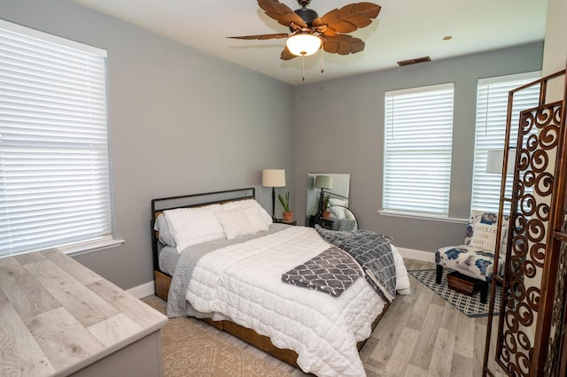 bedroom featuring multiple windows, light wood-style floors, and baseboards