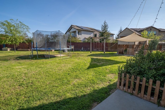view of yard with a trampoline and a fenced backyard