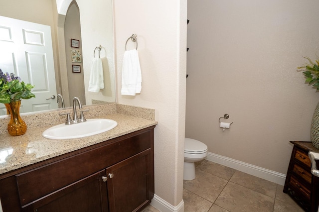 bathroom with baseboards, toilet, tile patterned flooring, and vanity