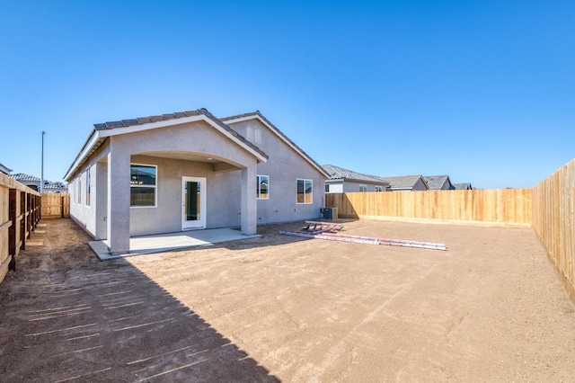rear view of house featuring a fenced backyard, a tile roof, a patio, and stucco siding