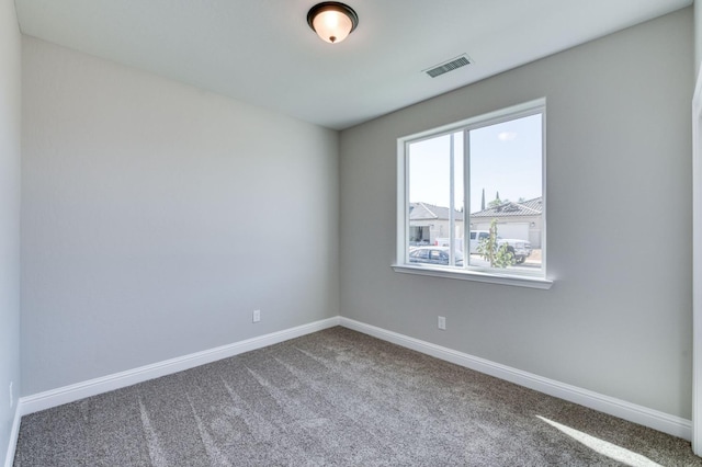 carpeted spare room with visible vents and baseboards