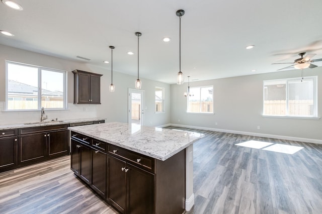 kitchen featuring light wood-style flooring, open floor plan, a sink, and baseboards